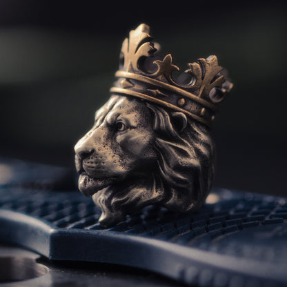 Macro close-up of the Lion King EDC bead showing the hand-aged lion face, layered mane, dark recessed details and brass crown.