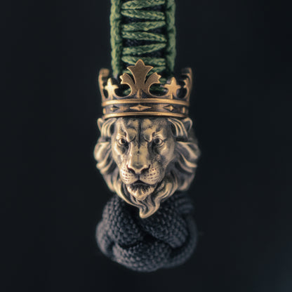 Front view of the ShadowEDC Lion King paracord bead with a sculpted lion face, layered mane and contrasting antique brass crown.