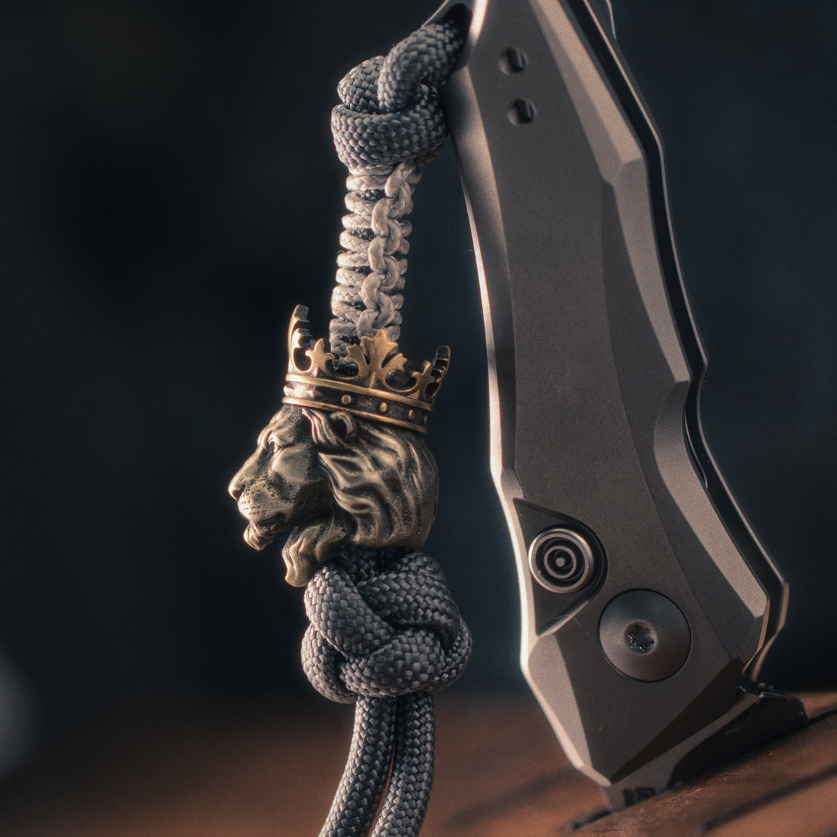 Side view of a crowned lion EDC bead mounted on paracord, highlighting the sculpted muzzle, flowing mane and brass crown.