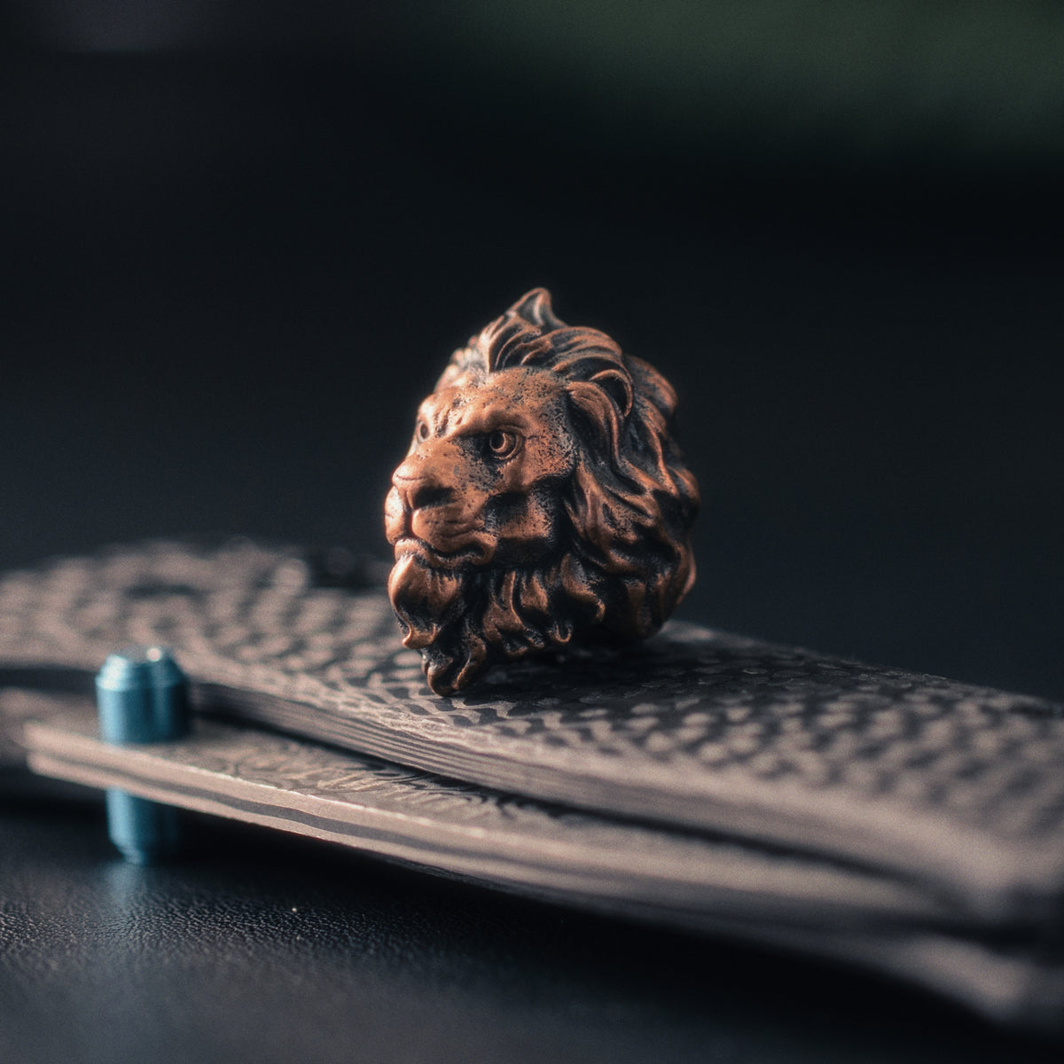 Three-quarter view of a Sculpted Lion paracord bead highlighting the facial structure, flowing mane and aged brass patina