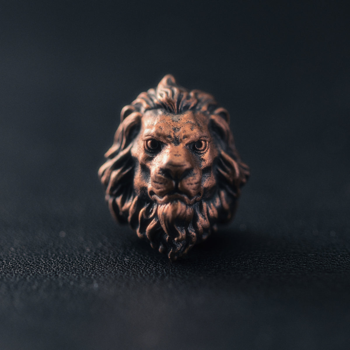 front view of a Sculpted Lion paracord bead highlighting the facial structure, flowing mane and aged brass patina