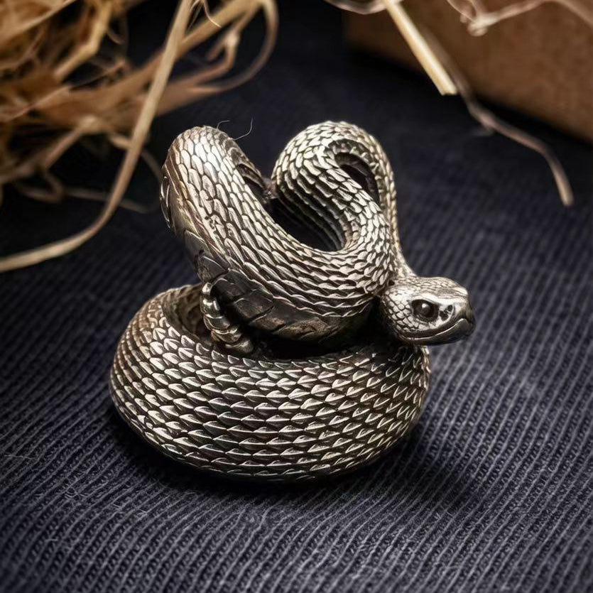 Side view of a white brass Rattlesnake paracord bead showing the sculpted snake head, curved body and detailed scale texture.