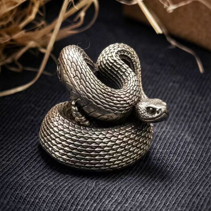 Side view of a white brass Rattlesnake paracord bead showing the sculpted snake head, curved body and detailed scale texture.