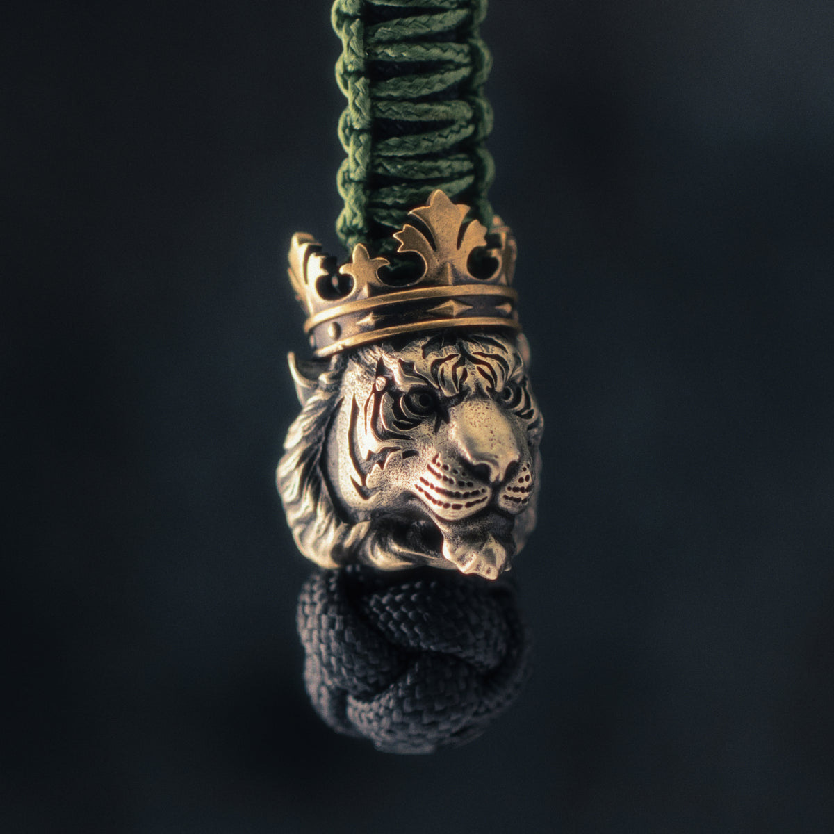 Side view of a crowned tiger paracord bead highlighting the detailed muzzle, layered fur, engraved stripes and aged brass crown.