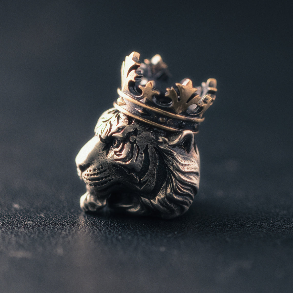 Profile view of a Tiger King knife lanyard bead with detailed tiger facial structure, layered fur and two-tone aged metal finish.